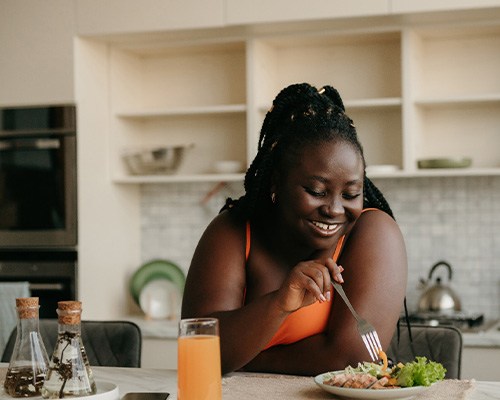 Woman smiling while eating lunch in kitchen