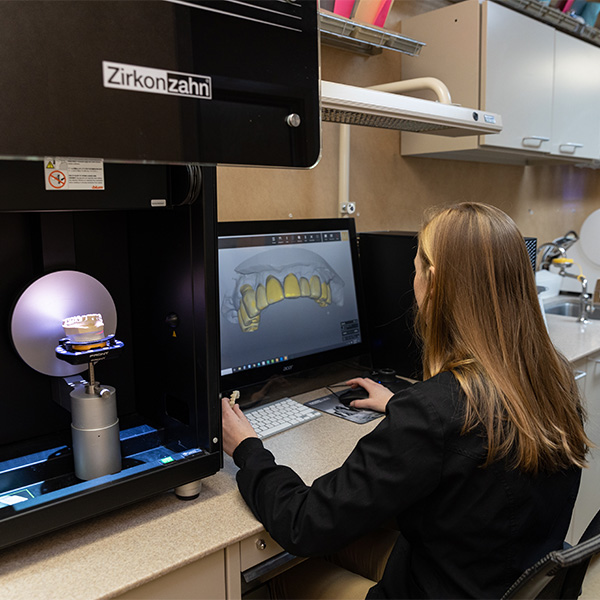 Gloved hands working on crown in dental lab