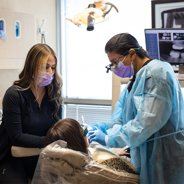 Dentist wearing mask and treating patient